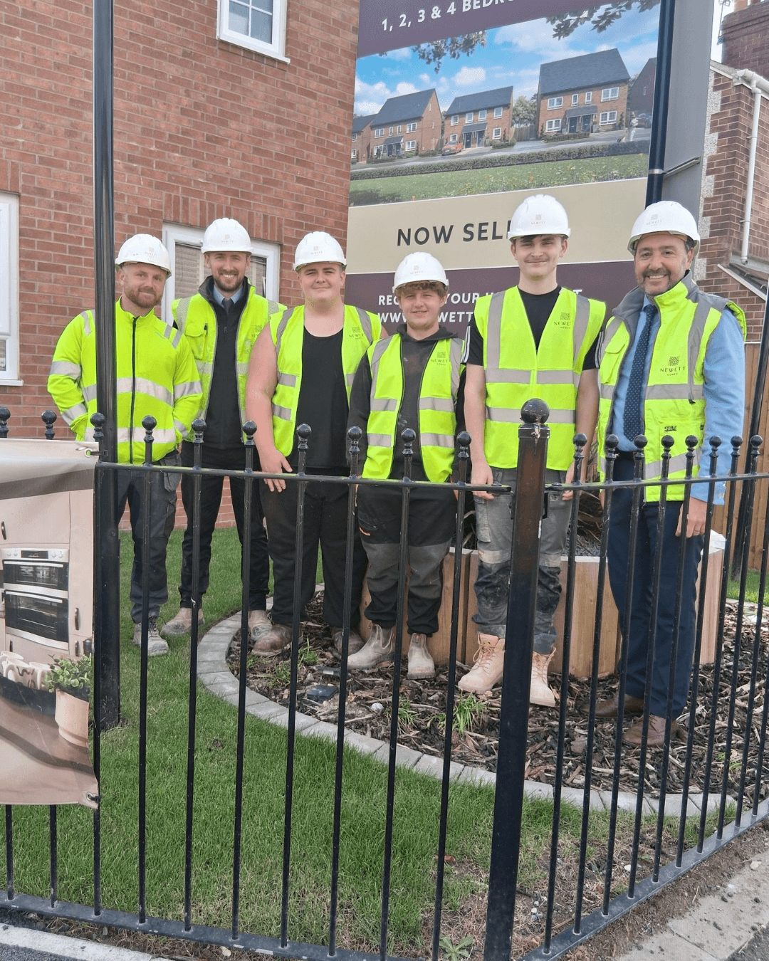 A group wearing hard hats at a Newett Homes construction site