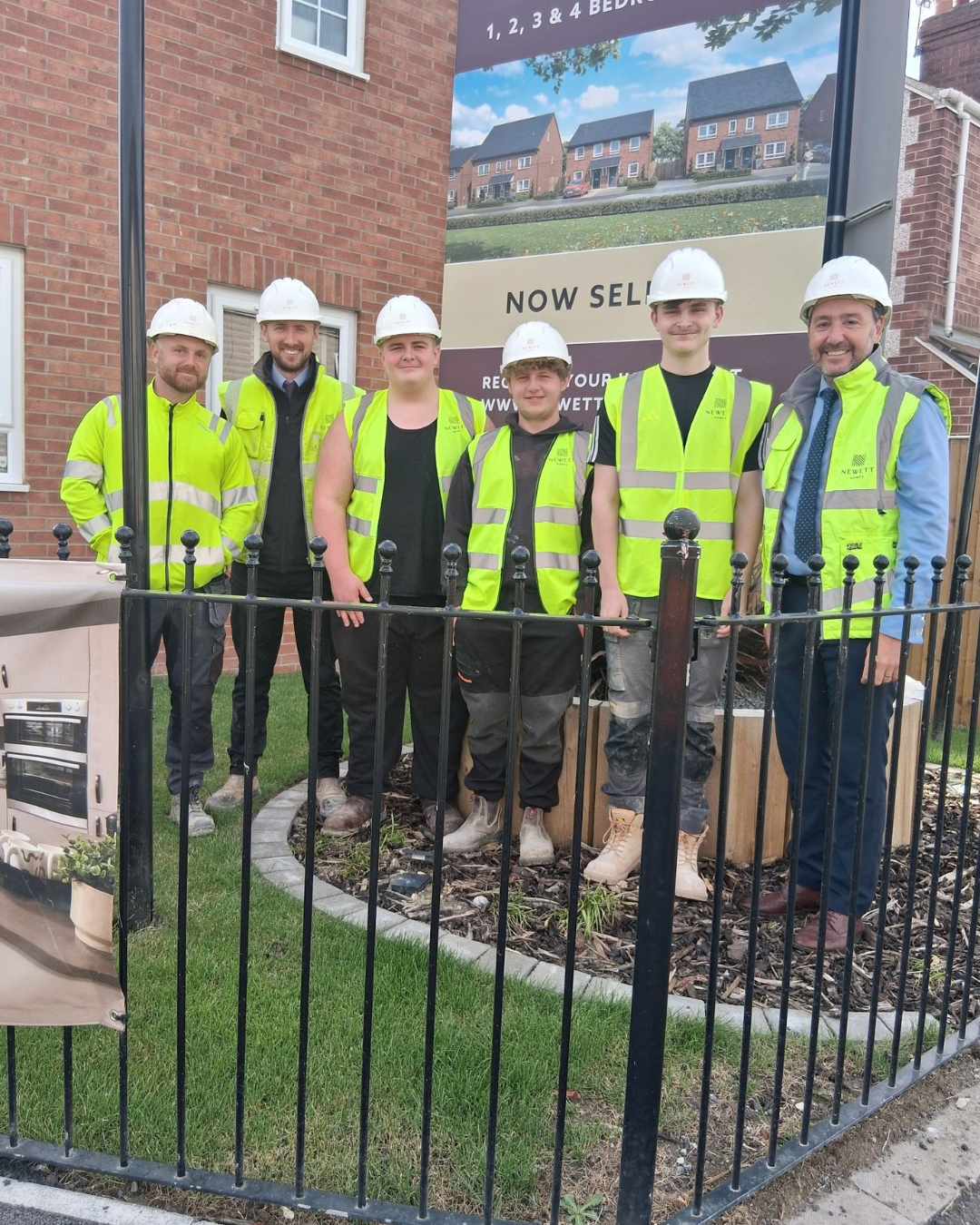 A group wearing hard hats at a Newett Homes construction site